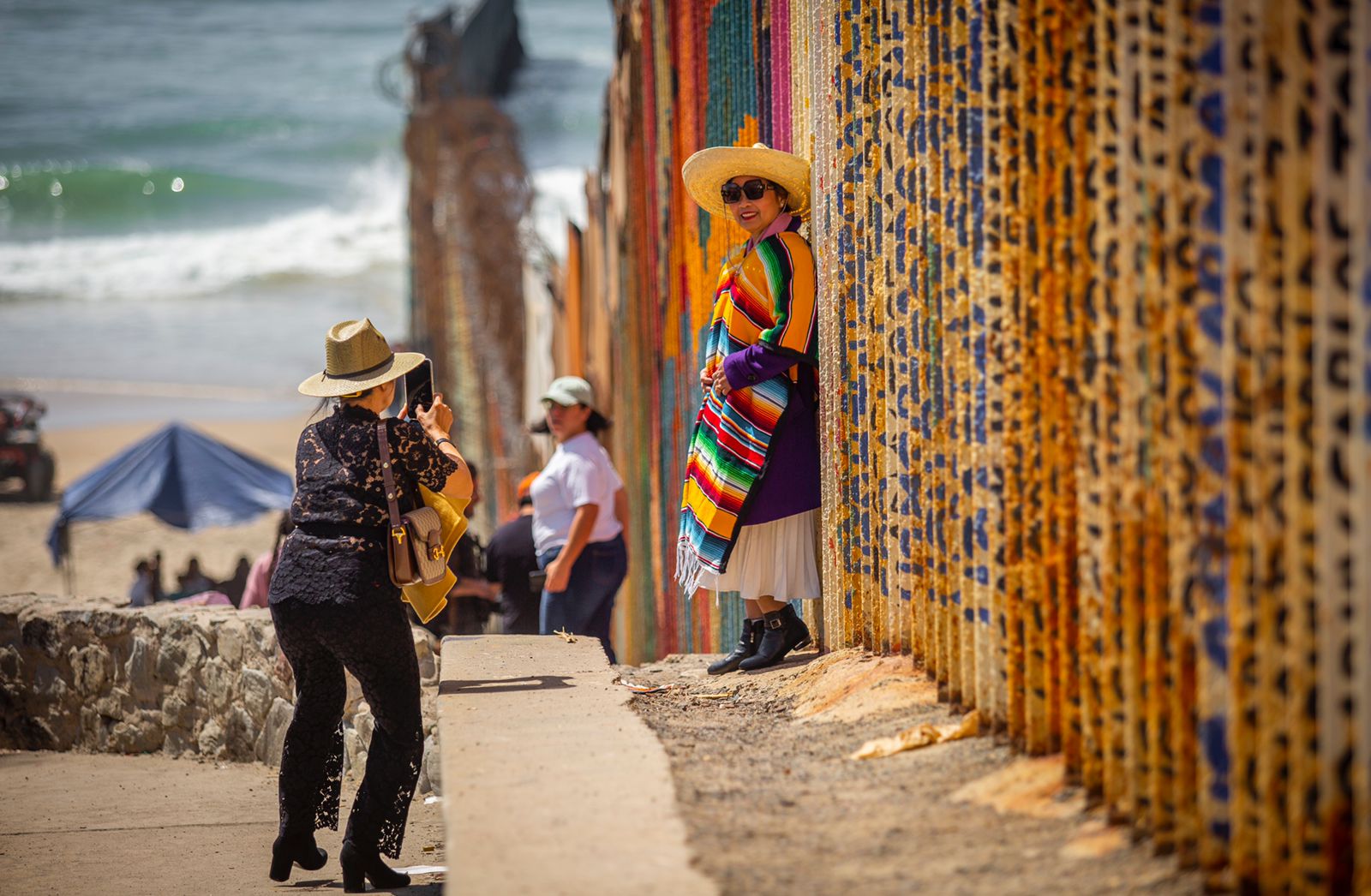 Fotonota Vestidos con un jorongo mexicano, turistas chinos se toman fotograf&iacute;as a un costado del muro fronterizo con Estados Unidos, en Playas de Tijuana