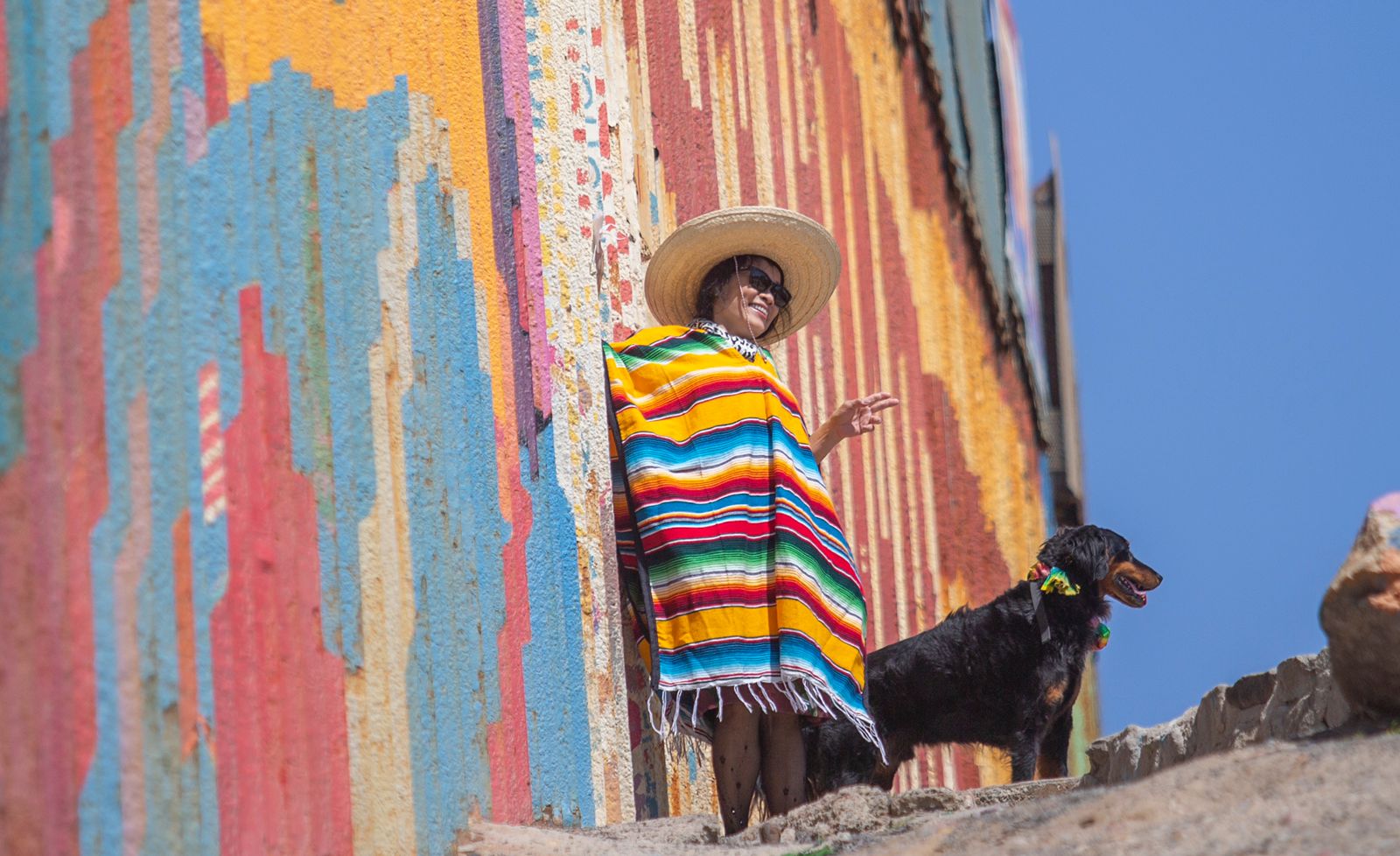 Fotonota Vestidos con un jorongo mexicano, turistas chinos se toman fotograf&iacute;as a un costado del muro fronterizo con Estados Unidos, en Playas de Tijuana
